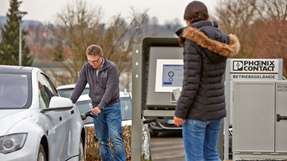 E-Parkplatz mit Terminal: Mitarbeiter von Phoenix Contact verbinden ihr E-Mobil mit dem Ladepunkt und melden ich mit dem Werksausausweis am Terminal an.