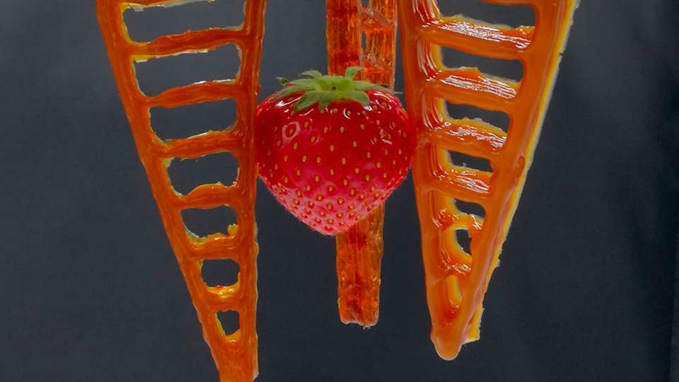 Ein 3D-gedruckter Greifer aus selbstheilendem Material hält eine Erdbeere.