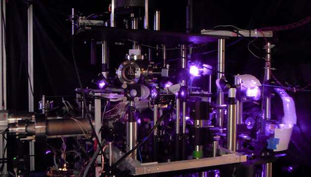 Das violette Glühen eines Infrarotlasers beleuchtet die optische Bank, die für das Experiment verwendet wird. Der Laser wird eingesetzt, um die Quantenzustände von Cäsiumatomen in einer Vakuumkammer präzise zu kontrollieren.