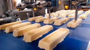 Premium-Fitnessriegel flexibel und präzise mit Topping versehen  Teigriegel auf dem Gurtförderer im Zulauf zur Dosierung